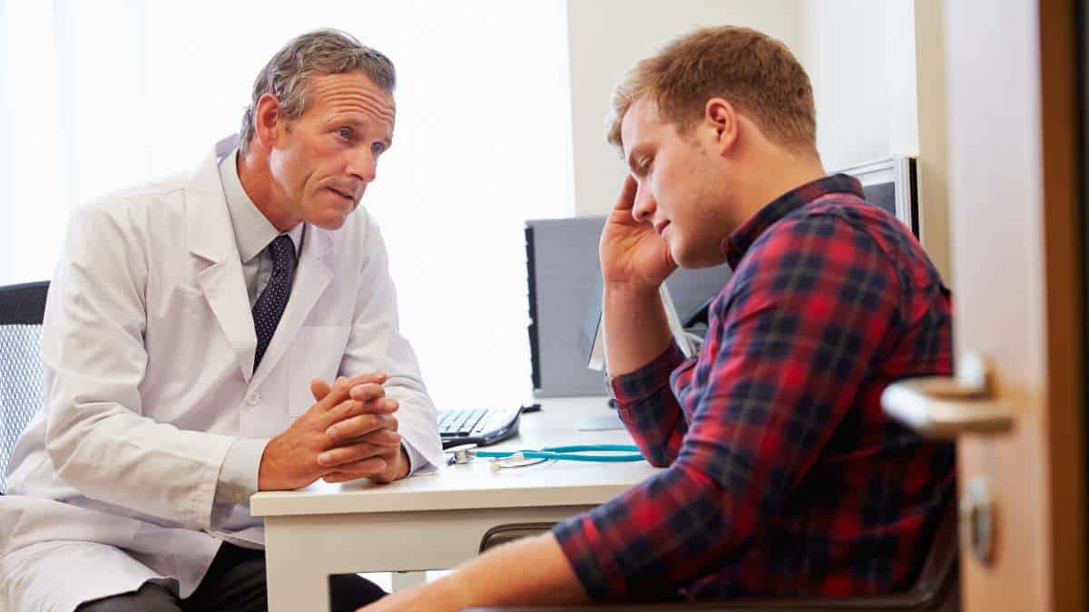 Medical specialist talking to a young man about the long term effects of meth addiction in a consulting room.